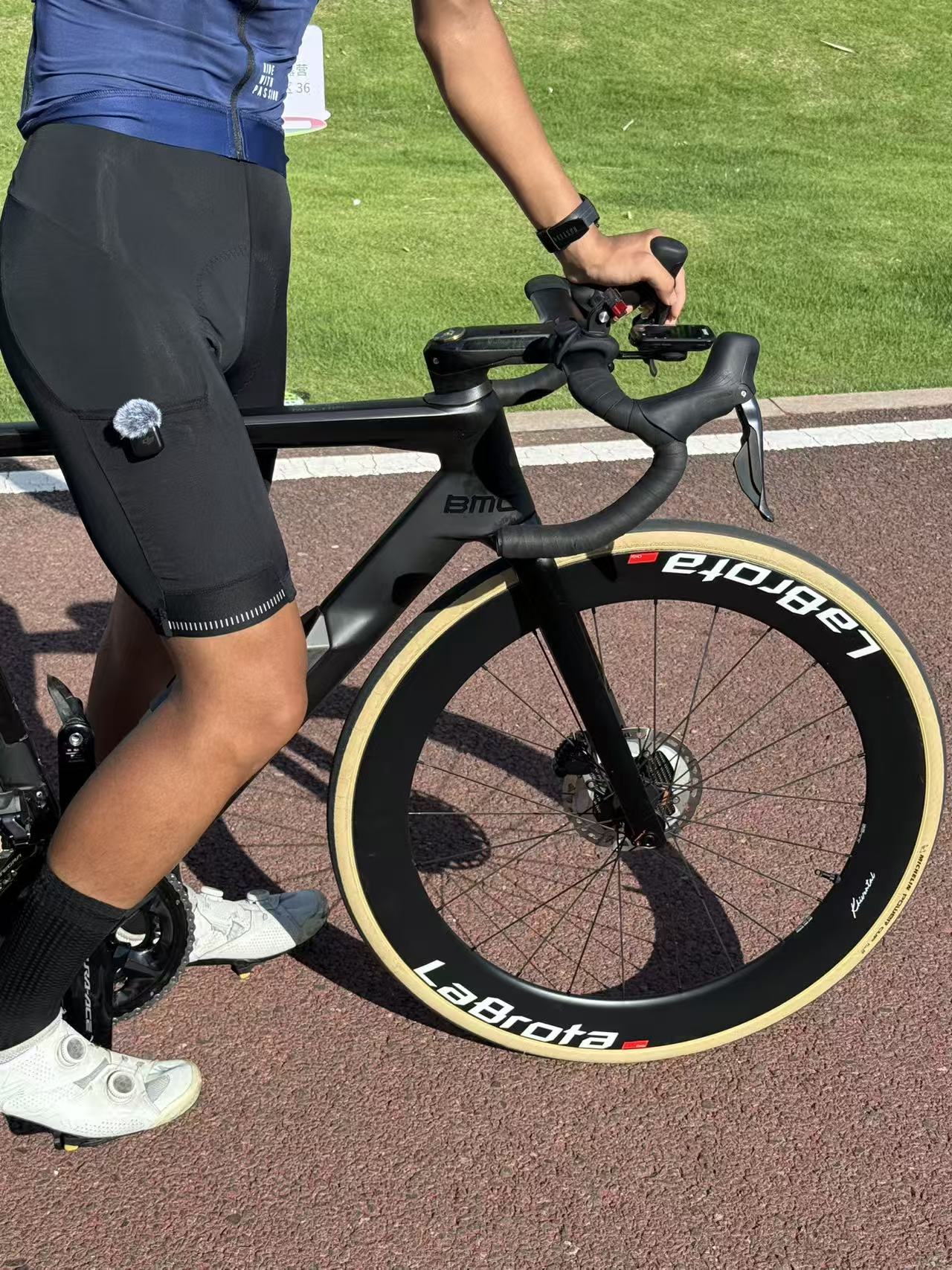 Close detail of Louis on a matte-black BMC road bike with LaBrota front wheel