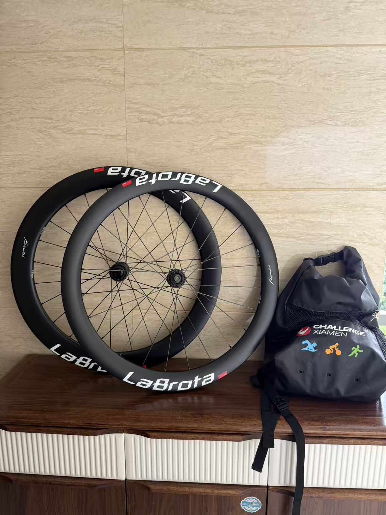 A pair of LaBrota wheels leaning indoors beside an event bag