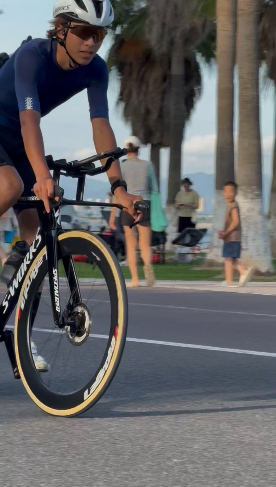 Front-quarter motion shot of Louis riding a black S-Works TT bike with LaBrota front wheel by the seaside
