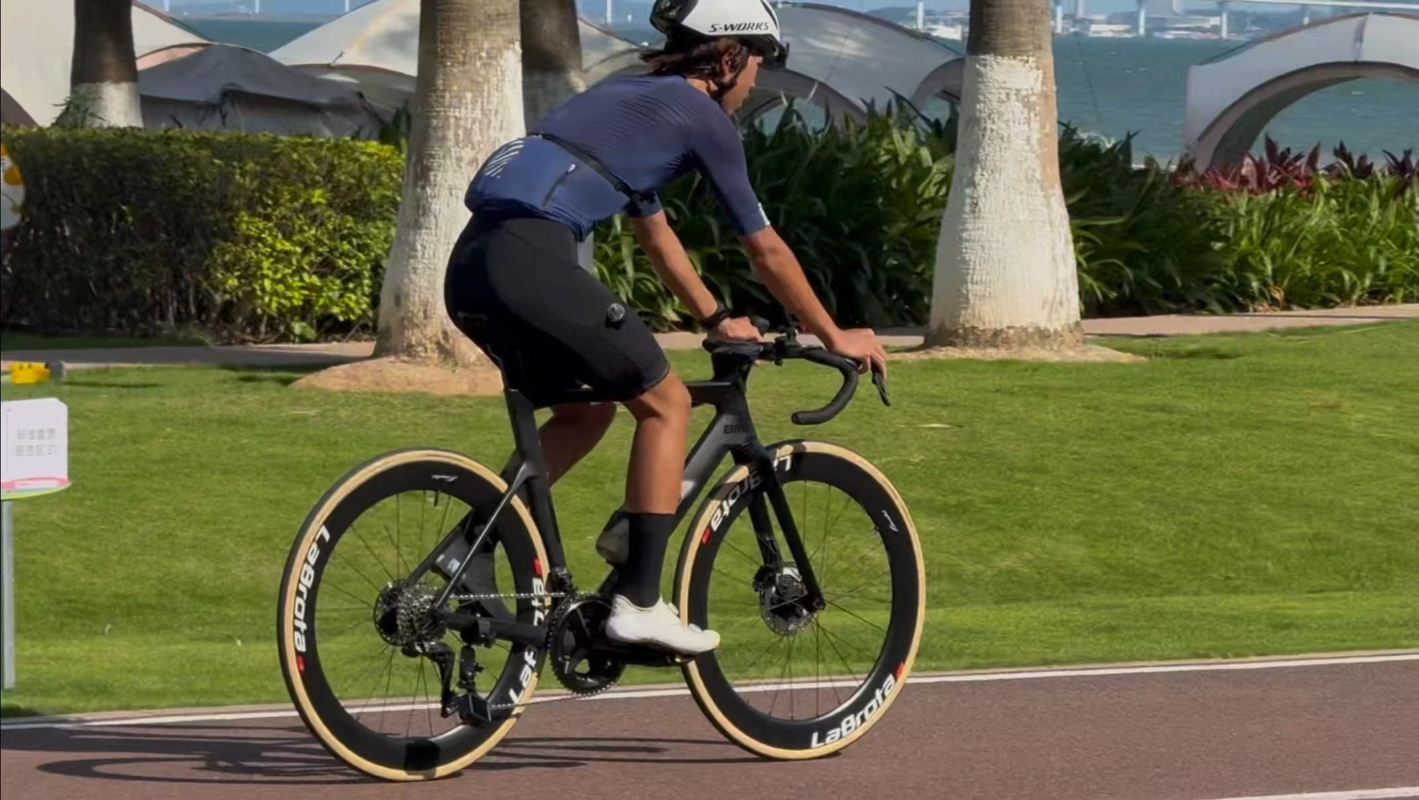 Side-profile riding shot of Louis on a matte-black BMC road bike with LaBrota wheels